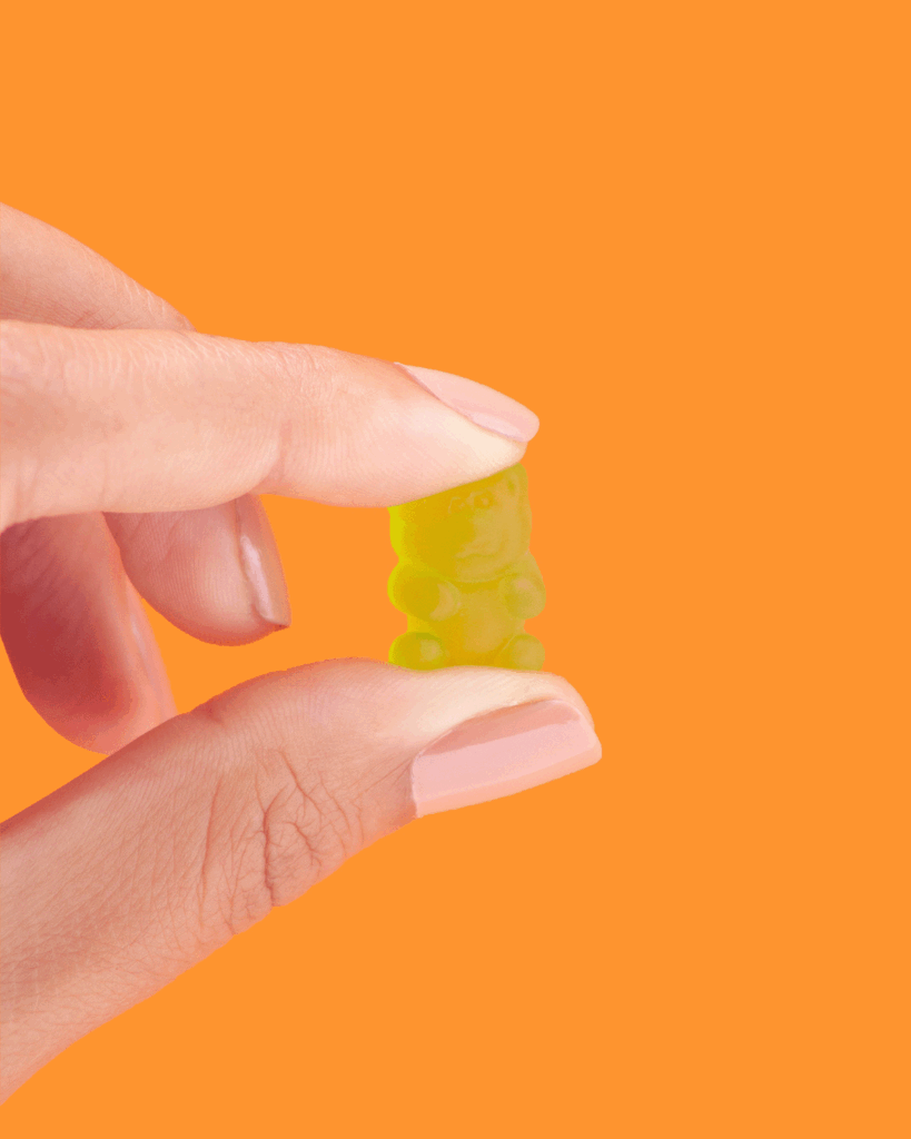 Gummy product shoot, A yellow Gummy Bear with Someone Holding it.