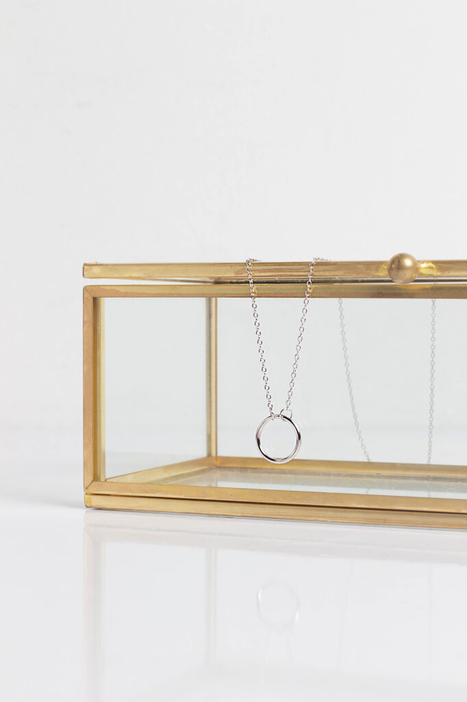 Silver necklace product photography on white background by Atlanta photographer Natalia Tamariz, showcasing elegant and high-quality jewelry for small brands. with gold holder.