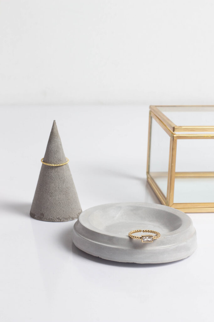 Two gold rings product photography on white background by Atlanta photographer Natalia Tamariz, showcasing elegant jewelry for small brands and a gold holder.